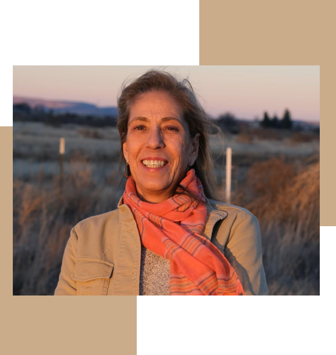 A woman wearing an orange scarf standing in front of some grass.